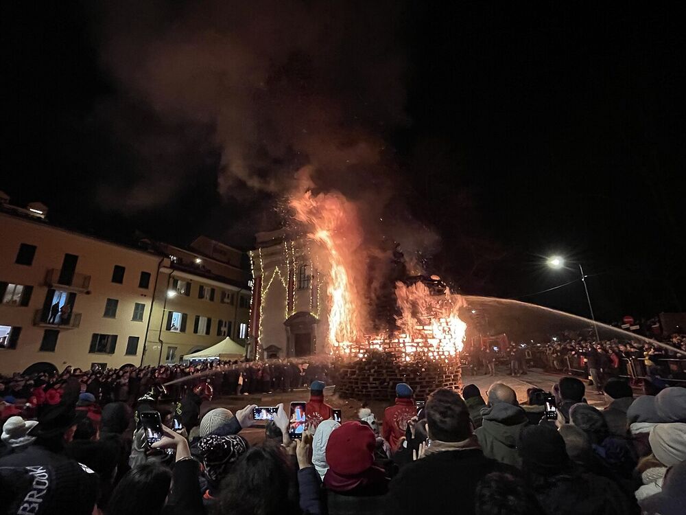 Un falò in una piazza di città circondato dalla folla